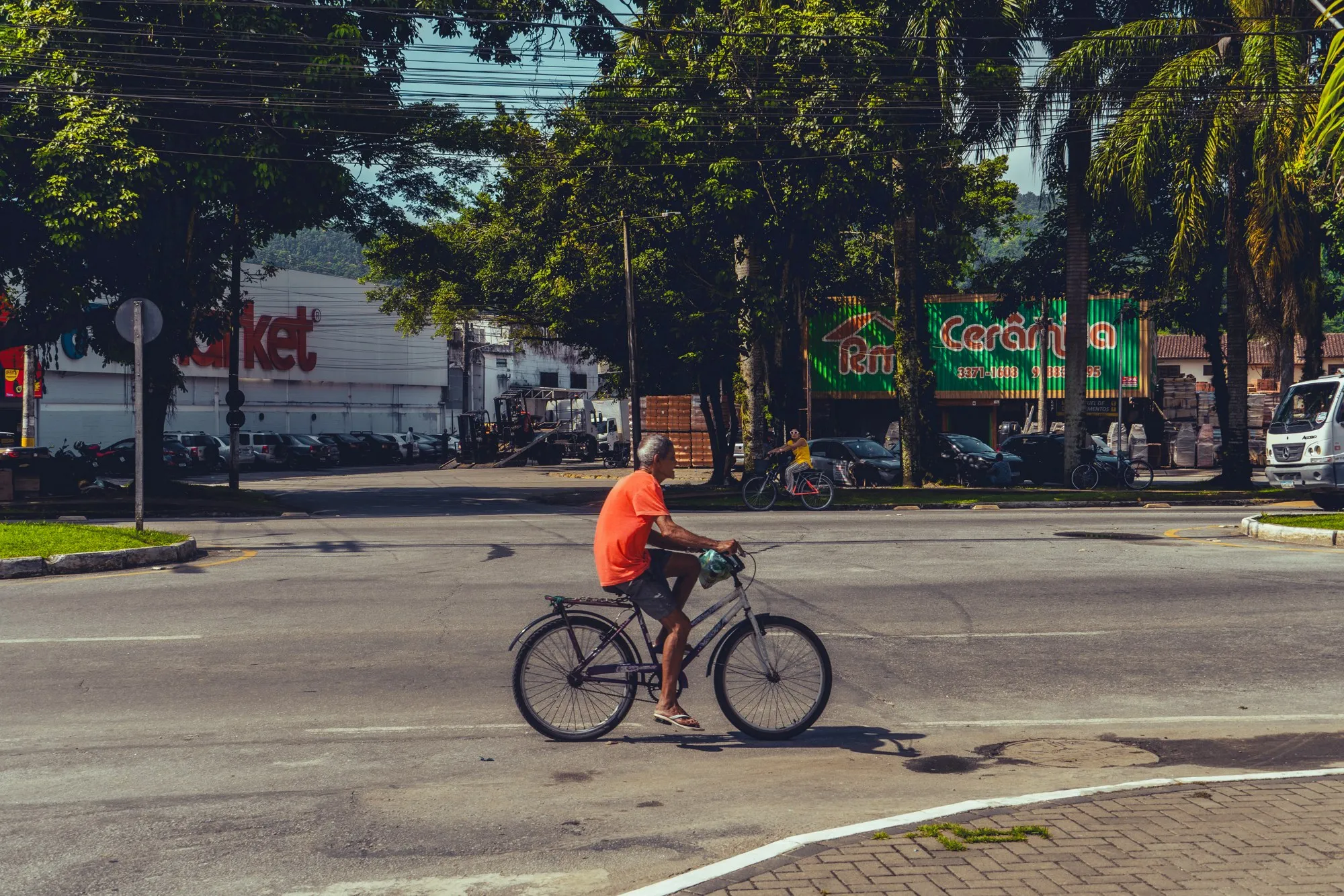 Un cycliste en t-shirt orange traverse un carrefour vide.