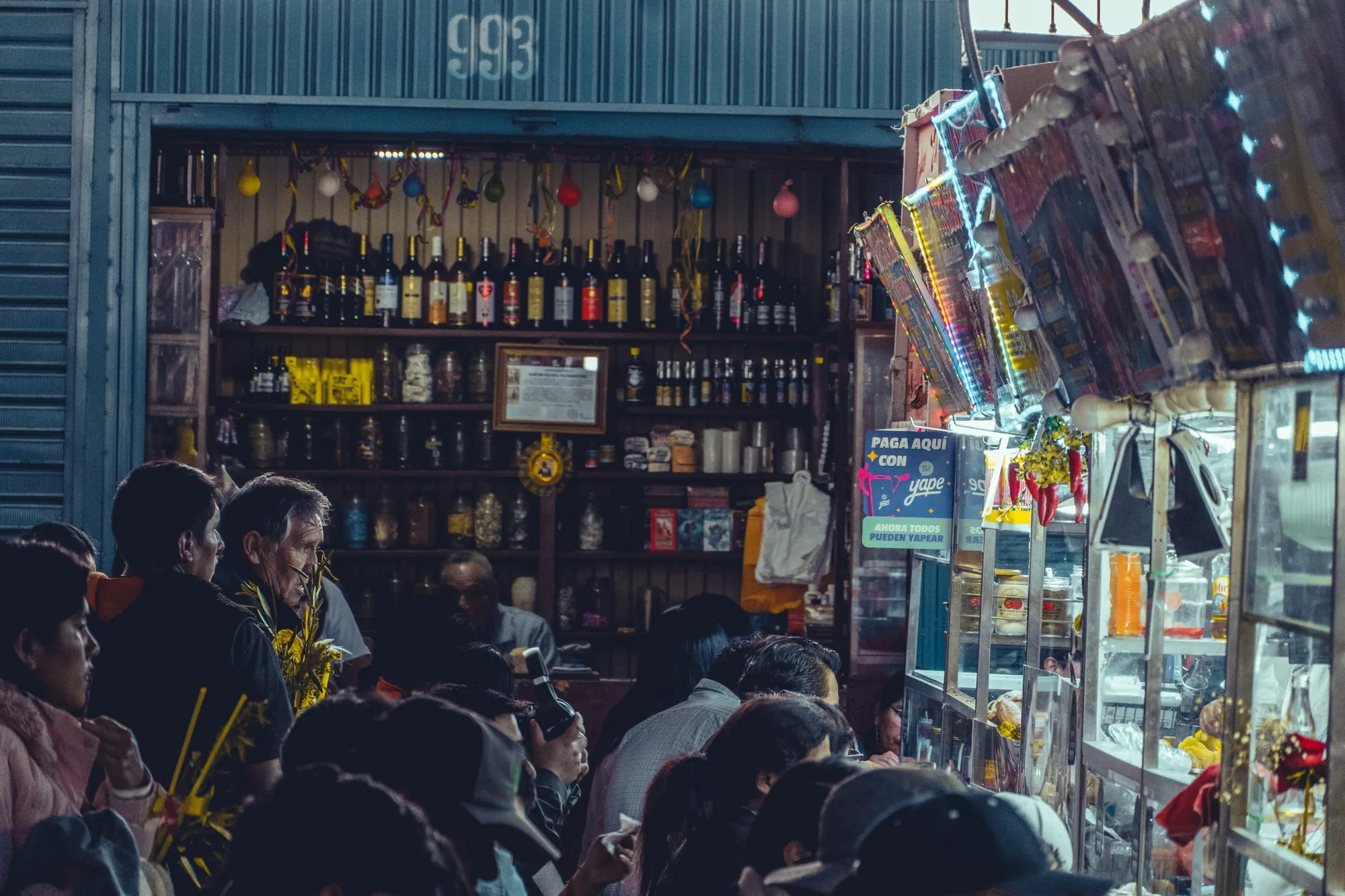 Des clients serrés devant un comptoir chargé de bouteilles et de bonbons.