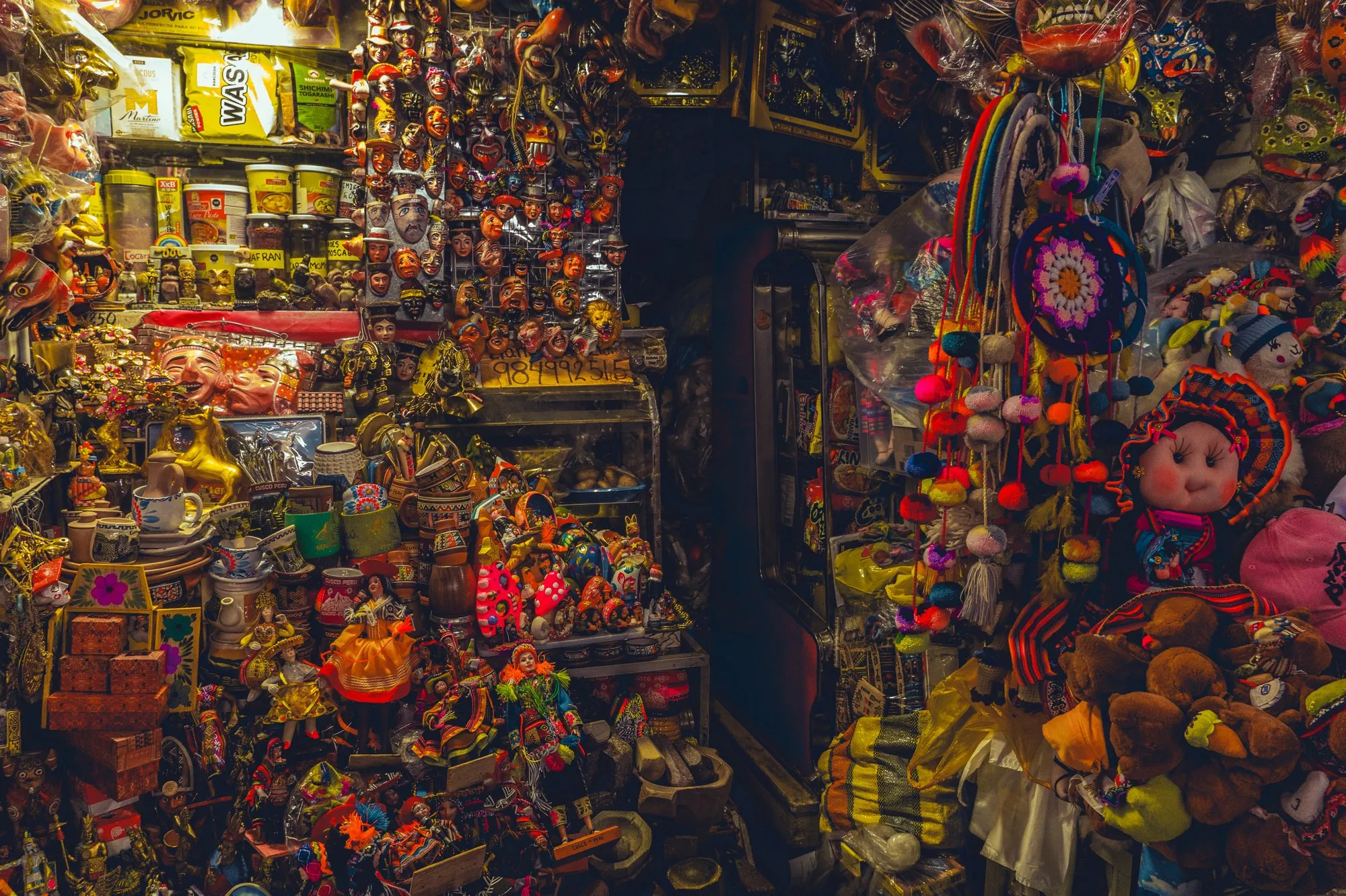 Un stand de marché déborde de poupées, de pompons et de jouets colorés.