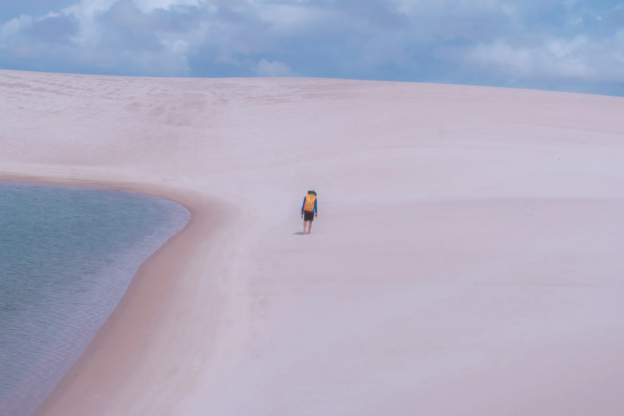 Une personne seule marche sur une langue de sable entre deux lagunes.